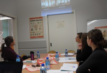 Zdjęcie przedstawia uczennice kierunku higienistka stomatologiczna realizujące kurs z zakresu periodontologii. Uczennice znajdują się w szkolnej pracowni Gabinet stomatologiczny.