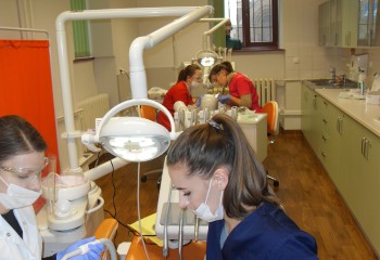 Zdjęcie przedstawia uczennice kierunku higienistka stomatologiczna realizujące kurs z zakresu periodontologii. Uczennice znajdują się w szkolnej pracowni Gabinet stomatologiczny.