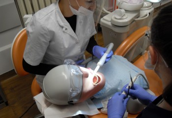 Zdjęcie przedstawia uczennice kierunku higienistka stomatologiczna realizujące kurs z zakresu periodontologii. Uczennice znajdują się w szkolnej pracowni Gabinet stomatologiczny.