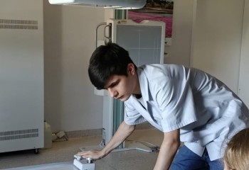 Zdjęcie przedstawia słuchacza wykonującego badanie diagnostyczne z zakresu elektrokardiologii. Widzimy aparat, słuchacza wykonującego badanie i pacjenta wewnątrz aparatu.