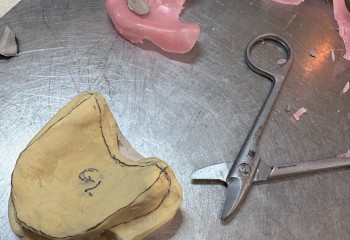 Zdjęcie przedstawia wykonaną pracę protetyczną oraz narzędzia protetyczne